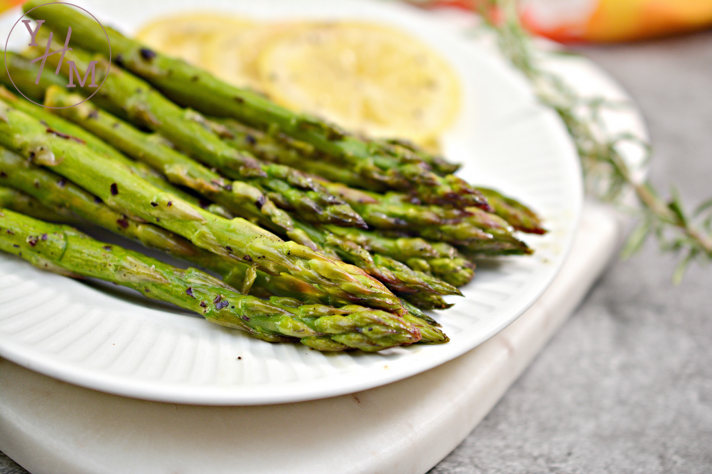 asparagus on white plate with slices of lemon